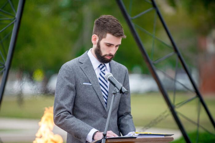 Young man speaking to audience at a veterans vigil.